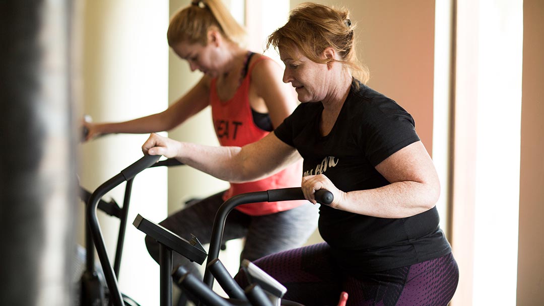 Two women using stationary exercise bikes